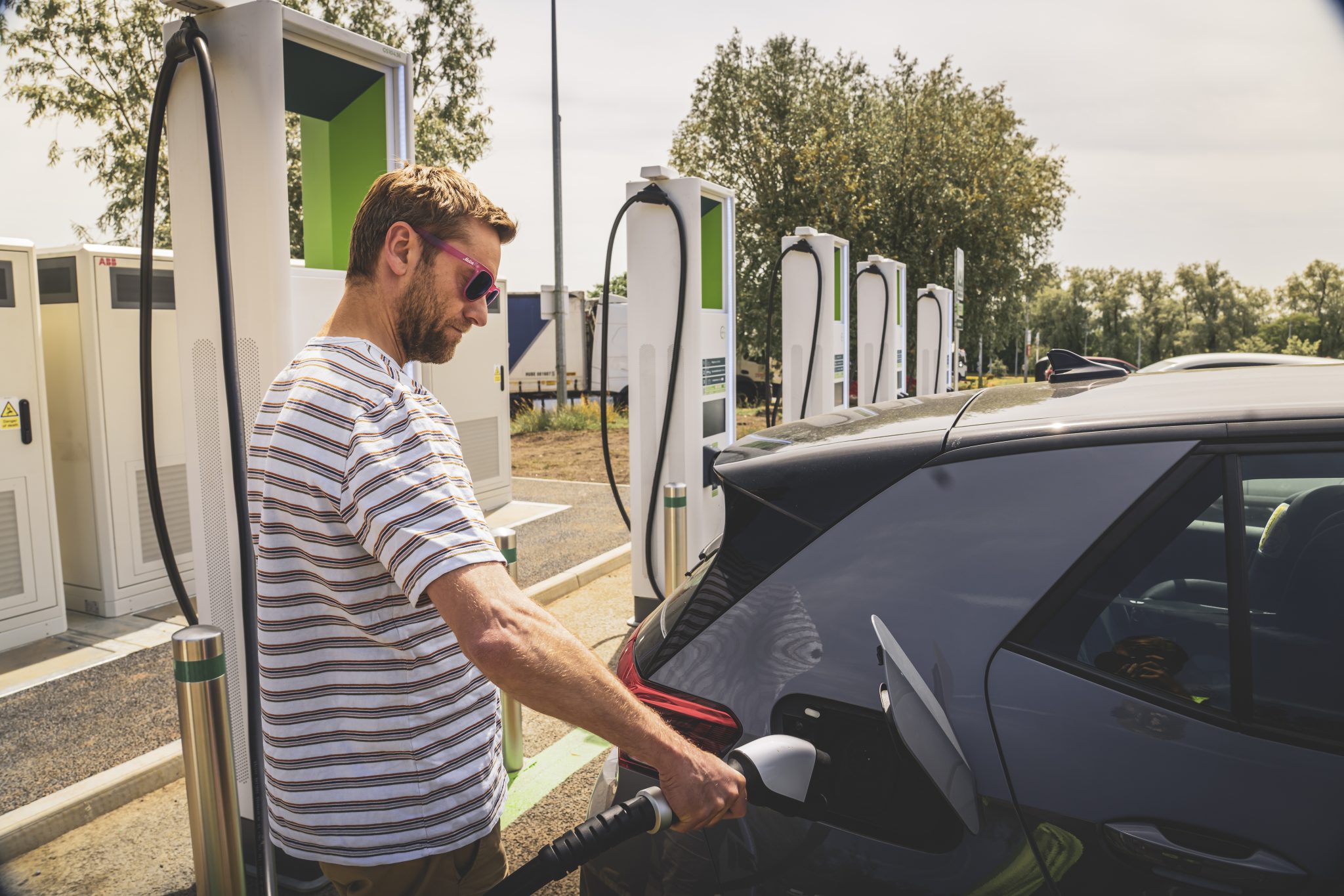 A man charges an electric car at a GRIDSERVE Charging Station