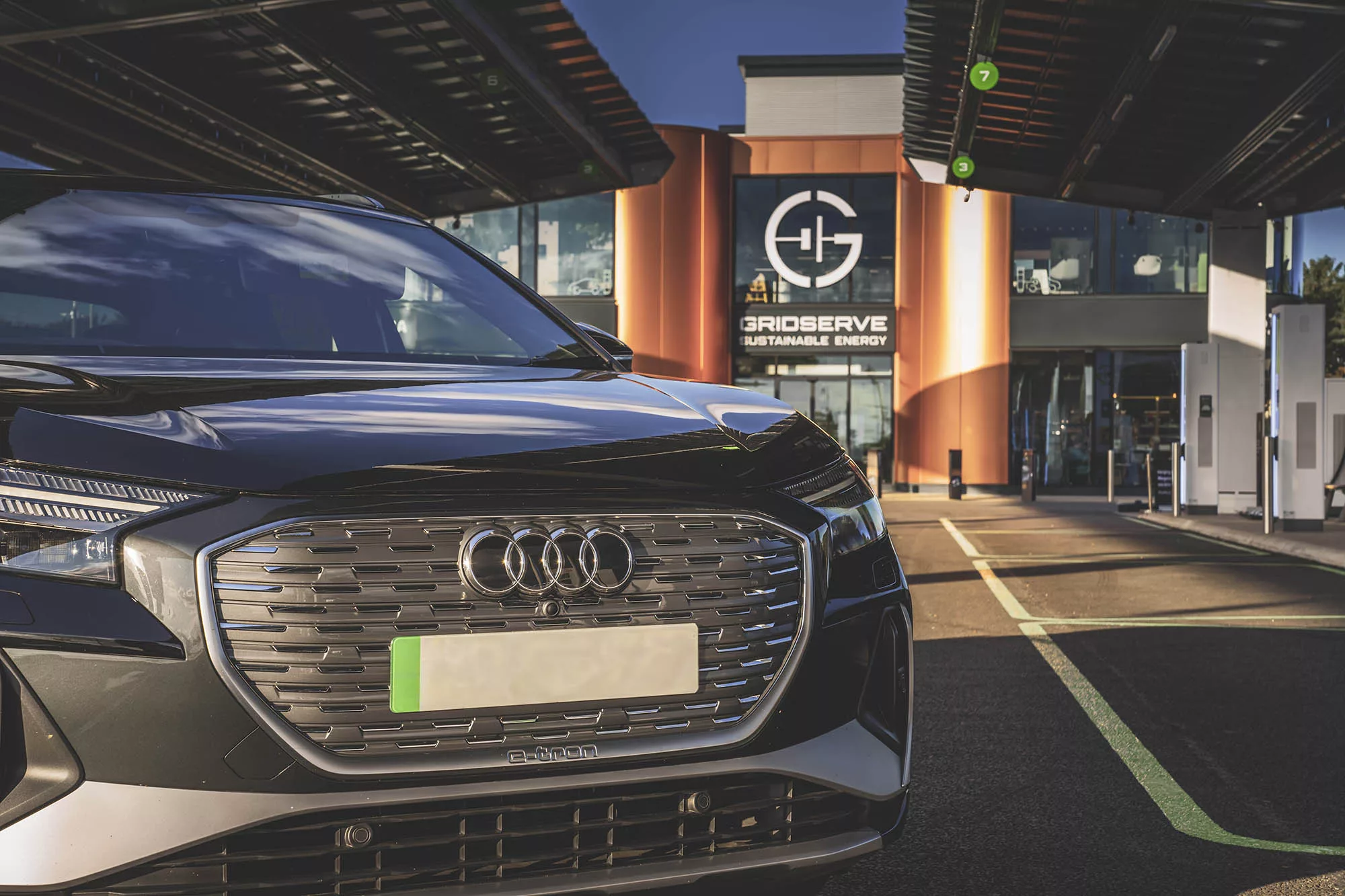 An Audi outside an Electric Forecourt. The green number plate is clearly visible.
